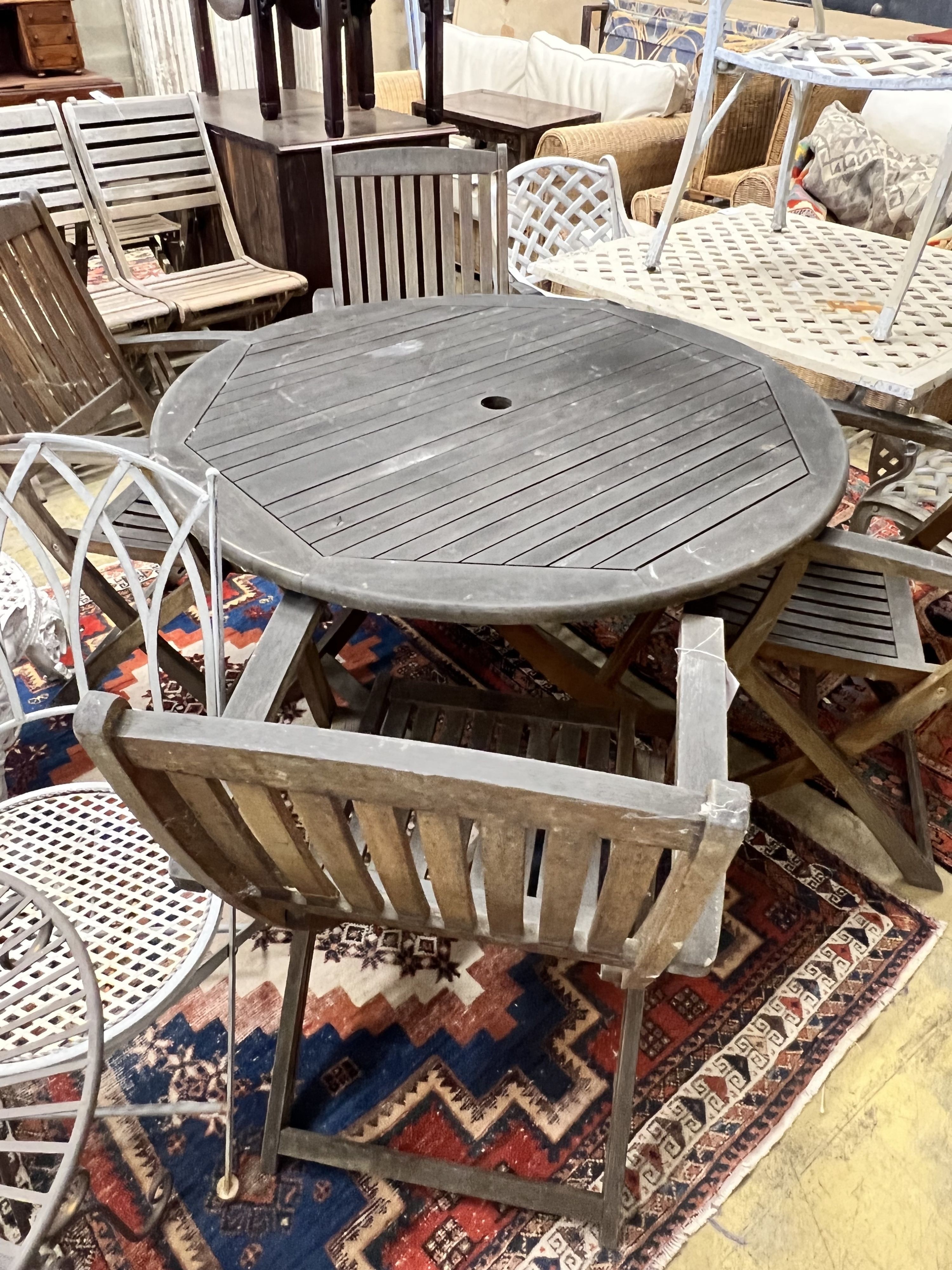 A circular weathered teak folding wooden garden table, diameter 110cm height 72cm, together with four elbow chairs